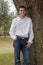 Young man stands by tree