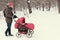Young man strolling pushchair with baby in winter park