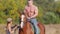 A young man with a strong physique sitting on a horse riding, a young woman instructor tells and shows how to move a man