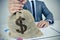 Young man in suit with a burlap money bag with the US dollar sig