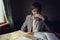 young man in a suit is sitting in a compartment of an old rare railway car, writing notes and crumpling sheets