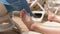 Young man sunbathing on a white plastic sunbed, detail to his feet, beach towel moving in slow wind background