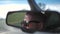 Young man in sunglasses is driving a car. Reflection face in rearview mirror of vehicle.