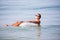 Young man in sunglasses with a glass of beer floating on rubber ring in the ocean water