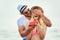 Young man suprising his girlfriend with gift on the beach