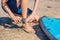 Young man surfer getting on the surfboard`s leash