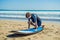 Young man surfer training before go to lineup on a sand beach. Learning to surf. Vacation concept. Summer holidays