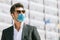 Young man with surgical face mask and sunglasses outdoors. Coronavirus personal protective equipment ppi. Modern building behind