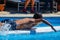 Young man swimming on surfboard in a pool