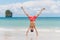 Young man in swimming trunks stands on his hands on sand against paradise tropical landscape - Railay Beach, Krabi, Thailand