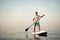 Young man in t-shirt and shorts floating on SUP board