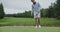 A young man takes aim and hits a ball with a golf club but fails