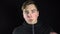 A young man takes off the mask of a balaclava. Bandit on a black background close-up.