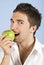 Young man taking bite of green apple