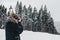 Young man taking photo with DSLR camera in Bukovel, Ukraine, on a cold snowy winter morning.