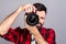 Young man taking photo with professional digital camera, focus on hand and lens