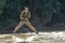 A young man taking a walk on the river performs various types of acrobatic tricks in the water in shallow water.