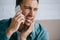 young man talking by smartphone and looking away while suffering from tooth pain at home