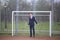 A young man, a teenager, in a classic suit. It is in the football goal, spread his hands.