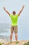 A young man on top of a mountain raised his hands up holding trekking poles