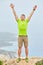 A young man on top of a mountain raised his hands up holding trekking poles