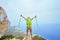 A young man on top of a mountain raised his hands up holding trekking poles