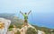 A young man on top of a mountain raised his hands up holding trekking poles