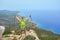 A young man on top of a mountain raised his hands up holding trekking poles