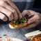 Young man tops a vegan appetizer with lettuce