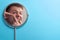 Young man touching his face and crushing pimple in mirror on blue background