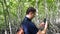Young Man Tourist with Backpack Makes Video on Smartphone in Mangrove Forest