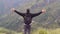 Young man tourist with backpack standing on the edge of beautiful canyon and victoriously raised hands. Male hiker