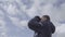 Young man tourist looking through binoculars. Sky clouds background 4k