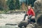 Young man tourist sits rocky mountain river bank