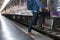 young man, tourist or traveler stepping up to the train on railway at train station. Travel, journey, trip concept