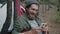 Young man tourist using smartphone touching screen and relaxing in hammock in forest