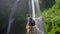 Young man tourist visits the biggest waterfall on the Bali island - the Sekumpul waterfall. Slowmotion shot. Travel to