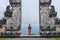 A young man in traditional clothes passes through the gate looking back. Ancient gate in Pure Lempuyan, Bali, Indonesia
