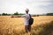 Young man traveler with backpack in hat stands in field at sunset and looks away, concept of freedom of choice, future, concept of