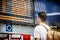 Young man traveling, reading train timetable in railway station