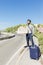 A young man travels hitchhiking. Stands on the highway with a sign.