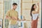 Young man with tray and paintroller standing against his wife with paintbrush