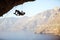 Young man trying to reach cliff in order to continue climbing