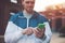 Young man typing message on his mobile phone, sunset on the street