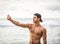 young man using cell phone to take photo, standing on a beach