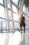 Young man using mobile phone app in airport. Young man texting smartphone walking inside office building or airport terminal