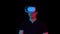 Young man in VR glasses. A man immersed in virtual reality makes movements with his hands. Blue and red light falls on a