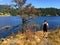 A young man walking along the path of the small Alexander island overlooking the ocean of west bay and mainland of Gambier Island