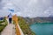 Young man walking in the border with a segurity wooden railing, with a beautiful view of the Quilotoa lake caldera