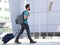 Young man walking outdoors with suitcase